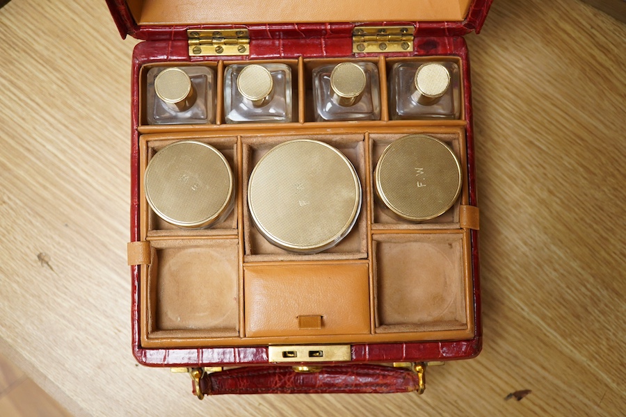 A red stained crocodile skin two layer vanity case, fitted with brass topped bottles and pots, case 22cm wide x 13.5cm high. Condition - handle has pulled away one side and needs re stitching